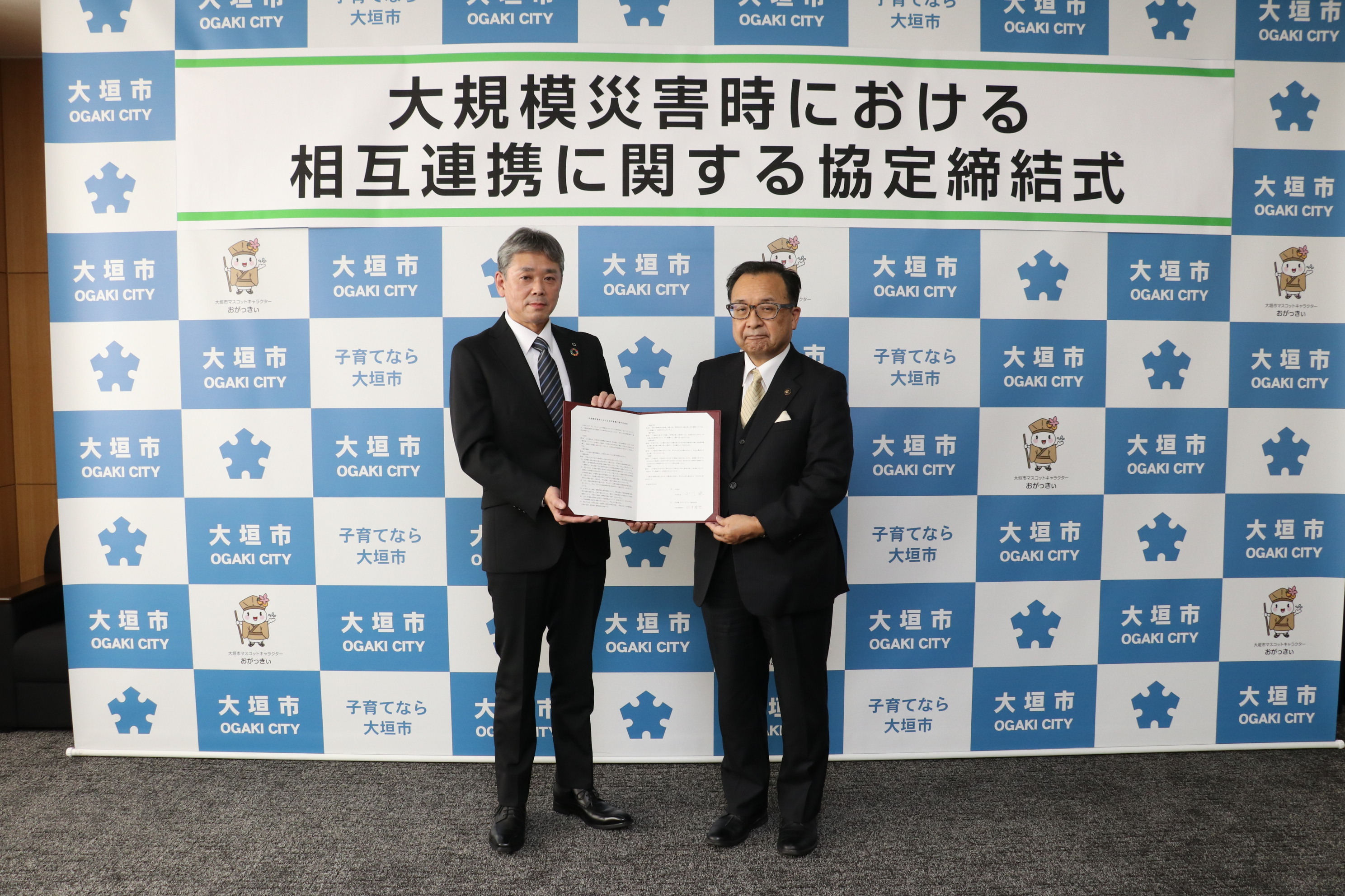 協定書を掲げる田中所長（左）と小川市長（右）