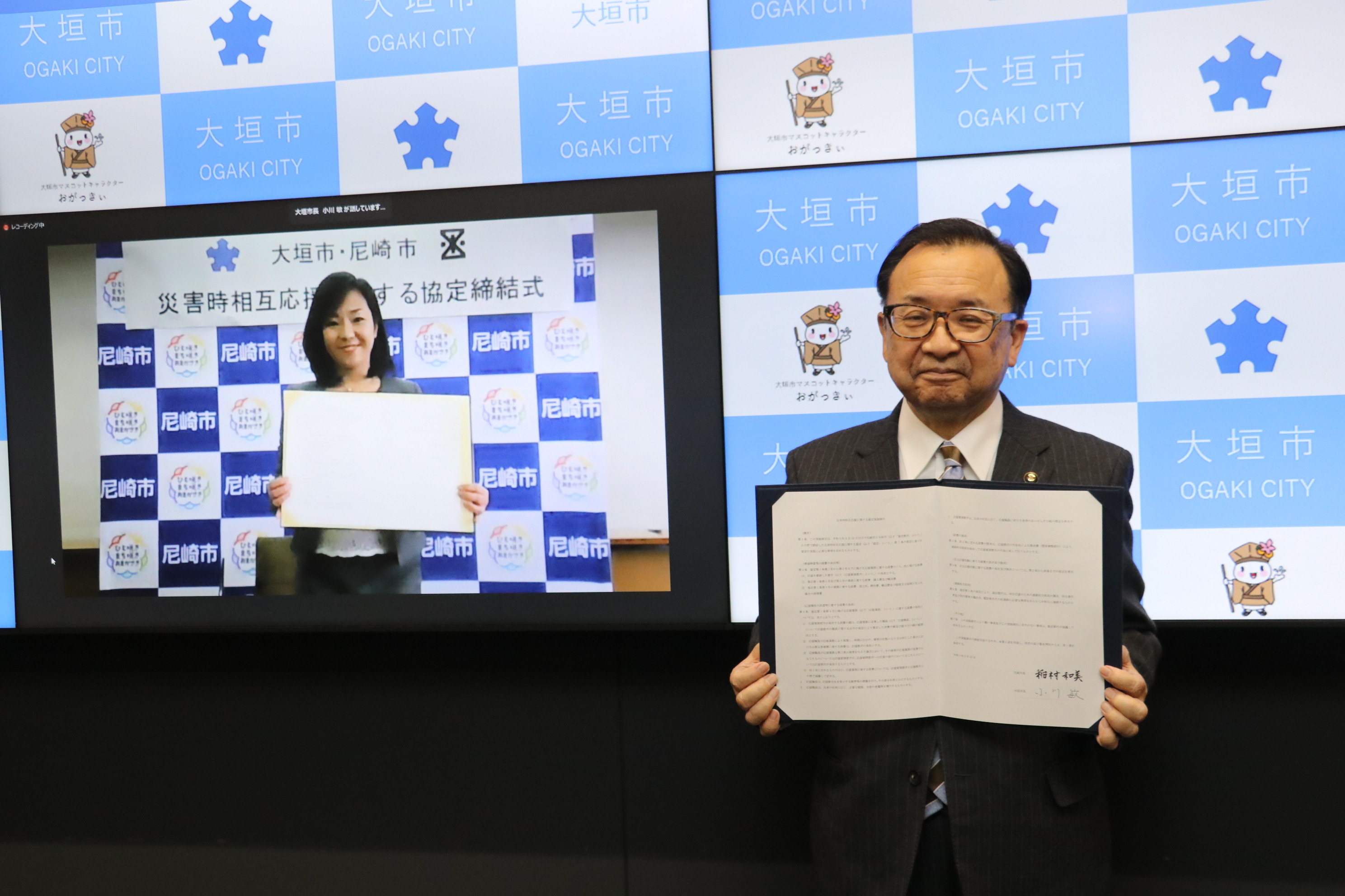 協定書を掲げる小川市長（右側から2人目）と稲村市長（左から2人目）